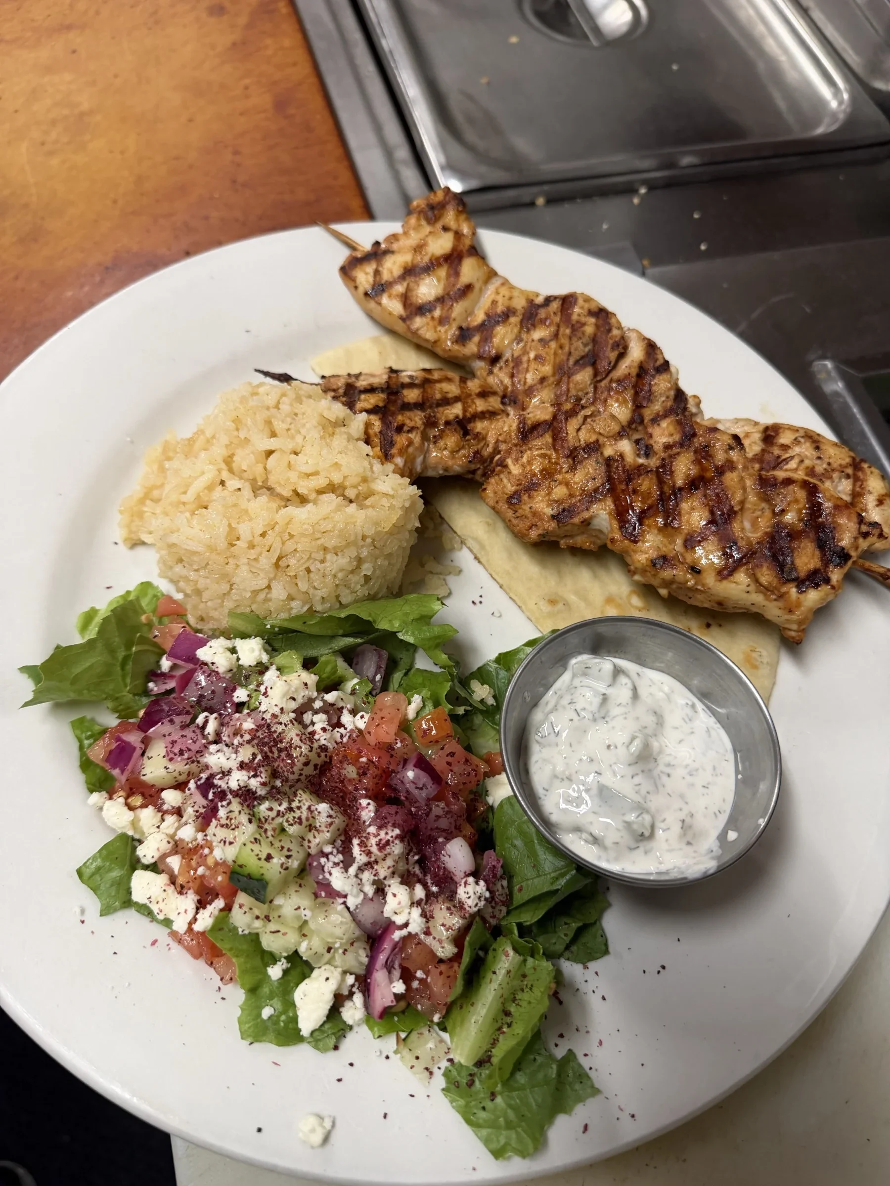 Grilled chicken kebab with rice, salad, and pita